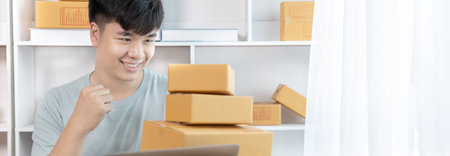 Young Asian man is writing down the customer's details and addresses on the notebook or box in order to prepare for shipping according to the information, Packing box, Sell online, freelance working.の写真素材