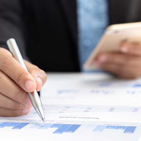 Financial businessmen use mobile phones to calculate income and analyze data about the company's...