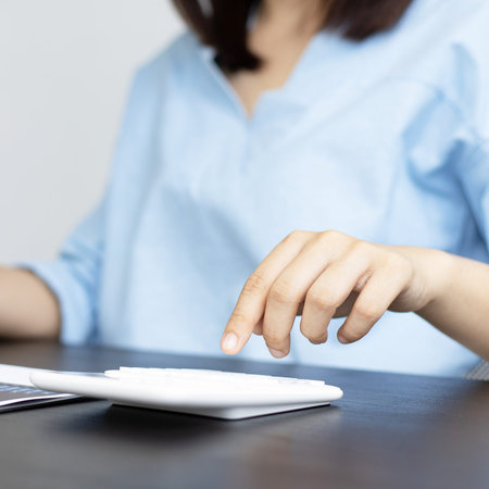 Female housekeepers are calculating using graphs and calculators to make family expenses in order to...