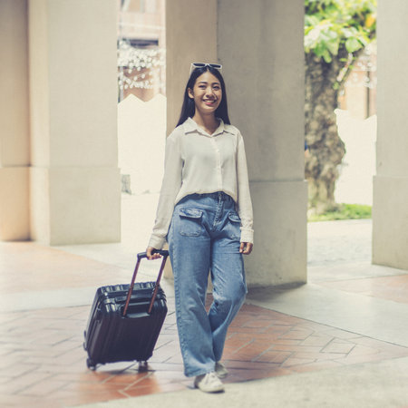 Asian woman beaming carrying a suitcase black to travel on vacation, Trolley bag, Long weekend travel, Love the trip, Tourism festival concept.の写真素材