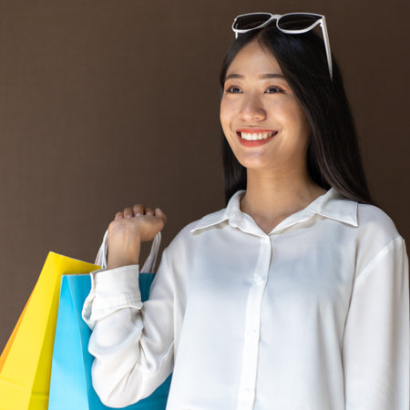 Text input box, Brown background, Young women carrying colorful shopping bags, Happy to buy products concept.の写真素材
