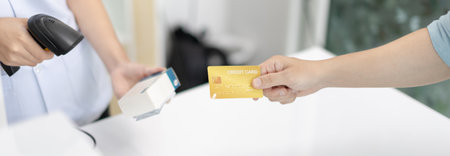 Credit card payment, Male patient pays by credit card to a pharmacist in a pharmacy, Get service at a community pharmacy , Pharmacist or cashier scanning medicinal products at checkout.の写真素材