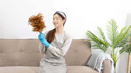 Beautiful Asian housewife wearing apron and cleaning gloves prepares to clean her house, Housework,...
