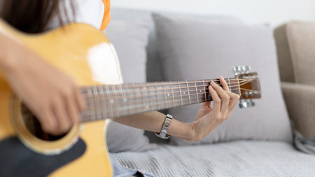 Woman practicing or learning to play guitar and practice using his fingers to hold guitar chords...