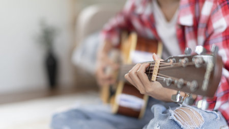 Woman practicing or learning to play guitar and practice using his fingers to hold guitar chords...