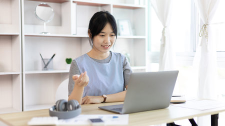 Young Asian women are greeting friends and teachers through video chats and greeting them with...