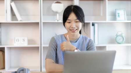Young Asian women are greeting friends and teachers through video chats and greeting them with cheerful expressions, Online communication , Stay home, New normal, VDO Call, Social distancing, Internet learning.の写真素材