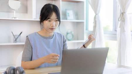 Young Asian women are greeting friends and teachers through video chats and greeting them with...
