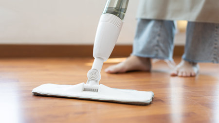 Young housewife mopping and cleaning the wooden floor, Use an antiseptic mop to clean the living...