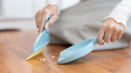 Close-up shot of hand holding a broom, Scooping rubbish into the dustpan, Cleaning scraps of paper...