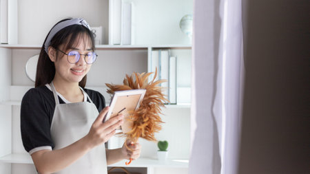 Housewife holding a dusting brush to clean things Pillows, rugs and other things in the living room,...