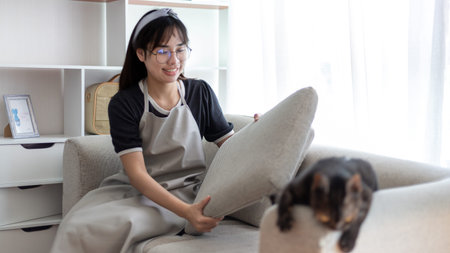 Young housewife tidying the sofa and cleaning in the living room, Big cleaning in the house, Removes...
