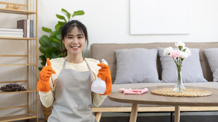 Beautiful Asian housewife wearing apron and cleaning gloves prepares to clean her house, Housework, Daily routine, Big cleaning, Clean and remove germs and dirt in the house, Clean up on weekends.の写真素材