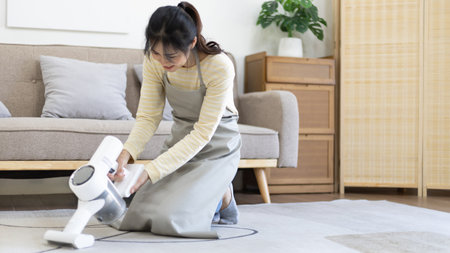 Beautiful woman vacuuming the floor and carpet in her living room, Big cleaning in the house, Removes germs, Housewife cleaning, Keeping her home clean, Domestic hygiene.の写真素材