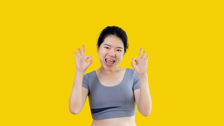 Young asian woman over white background doing ok sign with hands, OK symbol, Welcome, Agree, Join, Do as instructed, Follow orders, Acceptance of all conditions.の写真素材