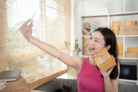 Woman uses his phone to take pictures of himself with products or selfies, Identity verification or order confirmation, Business style for working at home, Working at home and owning businesses.の写真素材