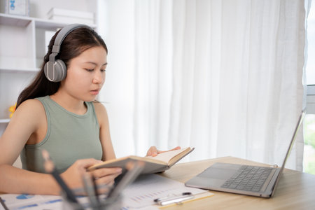 Young female student reading a book in a private office, Self study, Textbooks from books, Find out more, In the office there is a computer or laptop placed on the table, Study.の写真素材