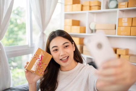 Entrepreneurial Woman Takes Selfies with Products for Online Sales, Working from Home, Identity Verification and Order Confirmation in Online Business, Capturing the Essence of Entrepreneurship.の写真素材