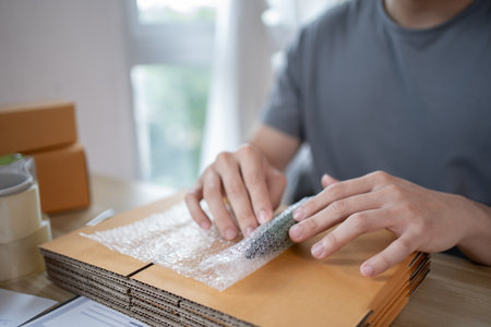 Efficient Home-Based Delivery, Man Packing Items into Post Box for Customer Shipping, Online Shopping and Small Business Entrepreneurship, Packing box, Sell online, Freelance working.の写真素材