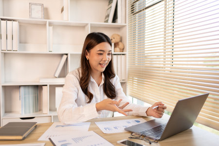 Young woman Working from Home, Video Call with Customer in Office, Remote Business Communication, Telecommuting Professional, Virtual Video Call with Office Customer, Work from Home Concept.の写真素材