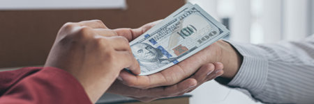 Businessmen give dollars to bribe employees in signing contracts to buy illegal land and real estate, Business fraud and social injustice, corruption and bribery concept.の写真素材