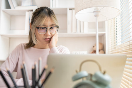 Young woman sitting at computer desk working, Analyzes data graphs on laptop, Works intently in his personal office, Work from home.の写真素材