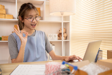 Sell products online, Young women are doing live or video calls with customers to place orders and prepare for delivery, Make The Ok Hand Sign to confirm and accept the order.の写真素材