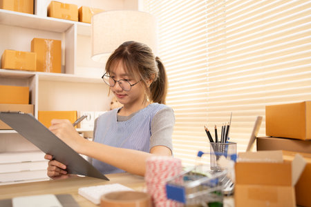 Check the product list, Online selling business, Small business owners are checking inventory in order to prepare them for proper delivery to customers,  Working from Home: Managing E-commerce Operations.の写真素材
