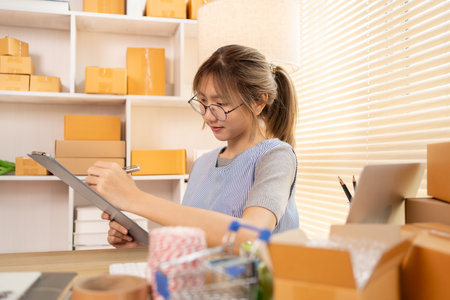 Check the product list, Online selling business, Small business owners are checking inventory in order to prepare them for proper delivery to customers,  Working from Home: Managing E-commerce Operations.の写真素材