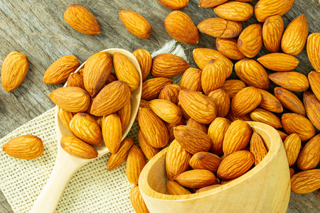 Top view macro almond nuts in a wooden spoon on a wooden background. Selective focus.の写真素材