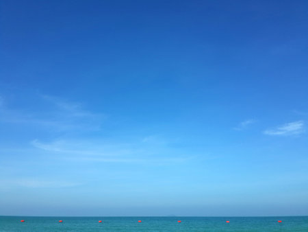 Clear blue sky on bright day with calm sea, that have a row of buoys.の写真素材