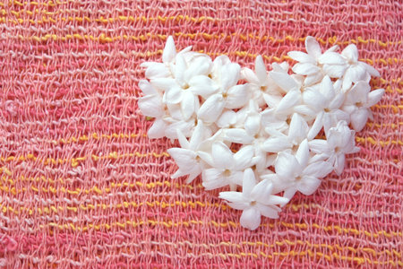 Heart shape of jasmine flower on the pink fabric background.の写真素材