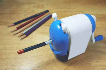 Pencil being sharpened in a pencil sharpener on wooden desk.の写真素材