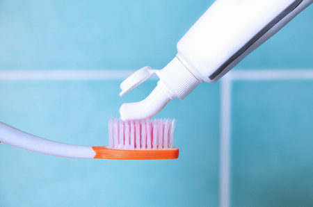 Toothpaste squeezed from tube onto brush, blurred background