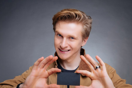 Man's hand showing business card - closeup shot on grey backgroundの写真素材