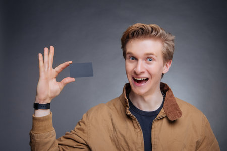 Man's hand showing business card - closeup shot on grey backgroundの写真素材