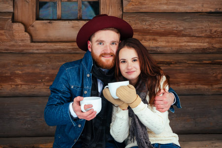 Happy couple drinking tea and wood old house