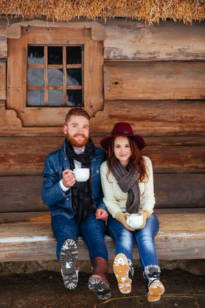 Happy couple drinking tea and wood old houseの写真素材