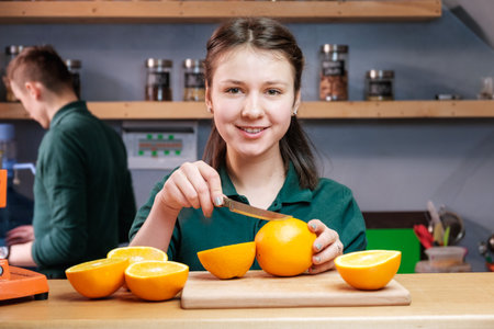 Beautiful girl making detox juice from orange with juicerの写真素材