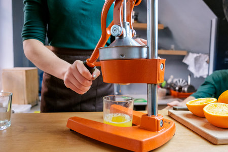 Beautiful girl making detox juice from orange with juicer