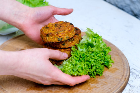 Fried vegetable patties on a plate. Yummy patties made of potatoes, green peas, carrot and green beans and garnished with fresh green onion. Veggie lunch or dinner idea.の写真素材