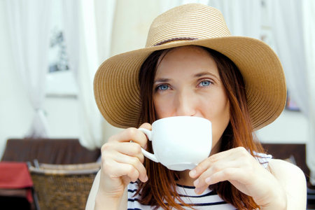 Portrait of a young brunette woman sitting and drinking teaの写真素材