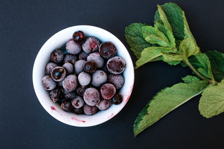 Frozen berries on a black background. With a sprig of mintの写真素材