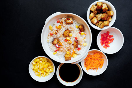 vegetarian rice salad with tofu and brown rice on black background.