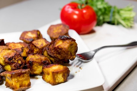 fried Indian slices of cottage cheese on a plate with tomato and roculaの写真素材