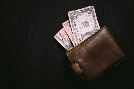 Old money bills in a vintage wallet. Flat lay of travel wooden desk