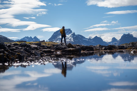 Guy travels with a yellow backpack through picturesque places with beautiful mountain landscapes.の写真素材