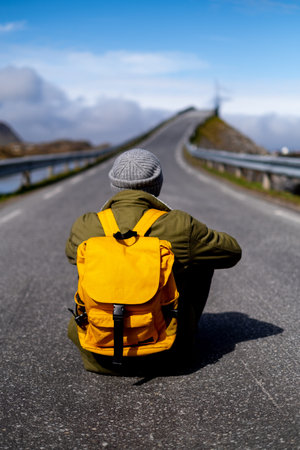 Guy travels with a yellow backpack through picturesque places with beautiful mountain landscapes.