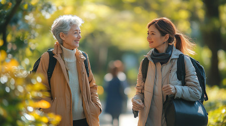 senior mother and adult daughter walking in autumn park, talking and smilingの素材
