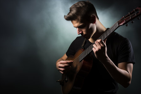 Young man playing the guitar on a dark background with smoke and fogの素材